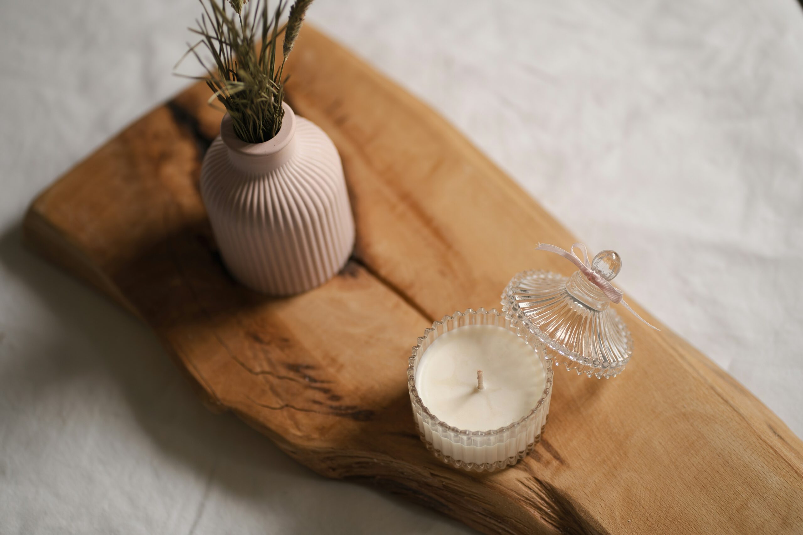 A wooden tray with a vase and a candle on it